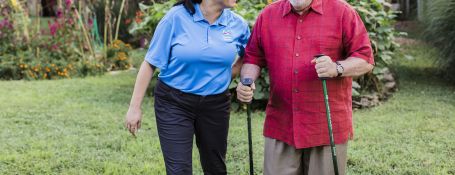Comfort Keeper assisting older gentleman using canes to walk