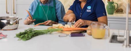 Senior and comfort keeper preparing food in kitchen