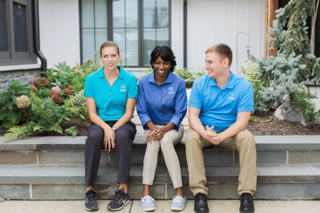 Photo of three Comfort Keepers caregivers sitter on the stone stairs and smiling