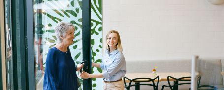 Caregiver holding the door open for her senior client