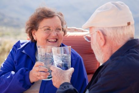 senior couple enjoying a glass of water together while siting outside