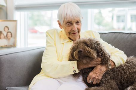 Older women with fluffy furry dog sitting on couch