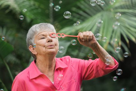 Senior blowing bubbles outside