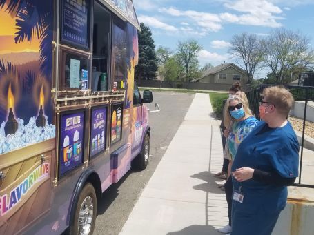 A purple food truck labeled "Kona Ice 2020" parked in front of a building in Colorado