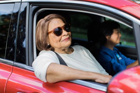 Senior in car being driven by caregiver