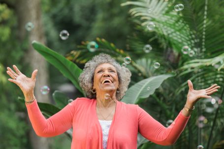 Senior blowing bubbles outside