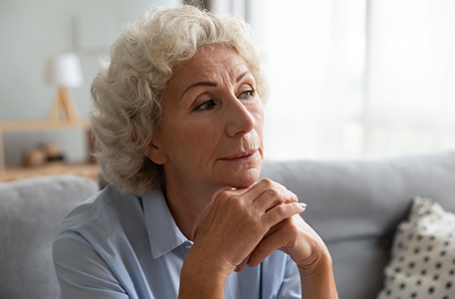 Pensive woman sitting on couch lost in thought