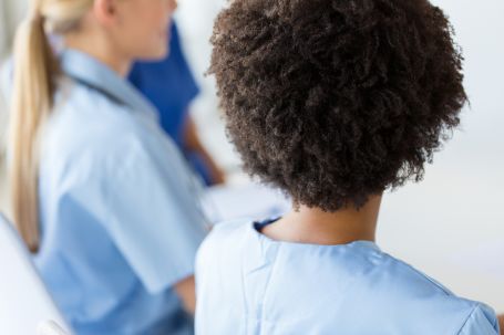Close-up of female CNA nurse with group from back.