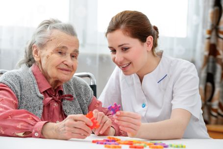 caretaker and elderly woman doing arts and crafts