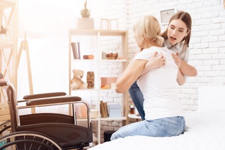 caretaker helping elderly women out of bed