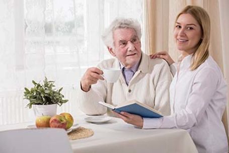 Caregiver reading to senior at kitchen table