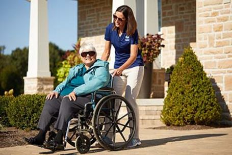 Caregiver with senior in wheelchair outside the home