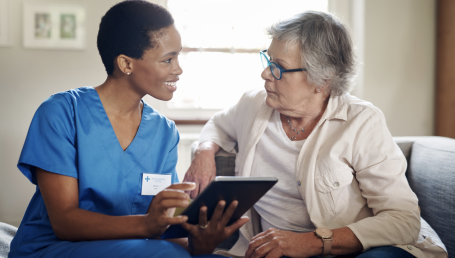 Caregiver showing a tablet to elderly woman