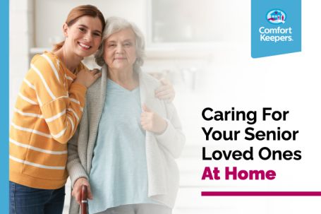 An elderly woman being hugged by a younger woman smiling.