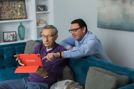 A younger man helping an older man with a computer tablet