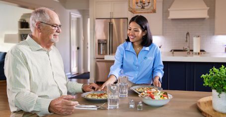 Caregiver helping senior man eat. 