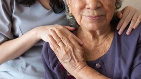 Elderly woman being comforted by caregiver. 