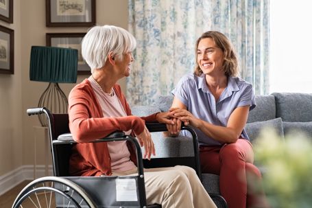 Woman caregiver assisting elderly woman in wheelchair 