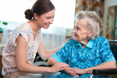 Female caregiver helping elderly person 