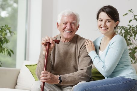 caregiver posing with senior man holding his cane 