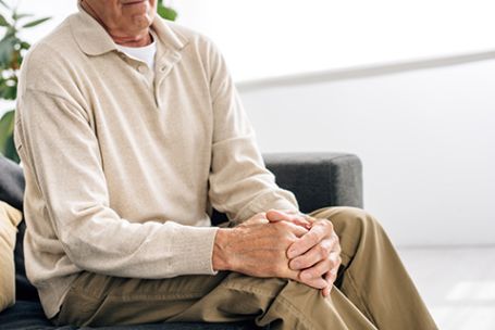 Delaware senior sitting inside clenching arthritic knee