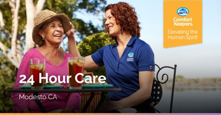 Younger woman happily fixing hat of elderly woman