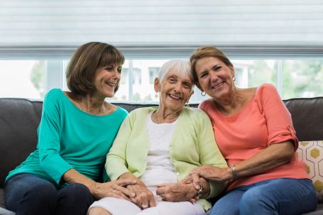 three ladies sitting on the couch smiling for the camera 