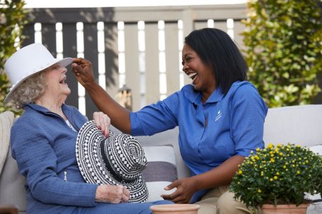 Caregiver and client sit outside and share a laugh together.
