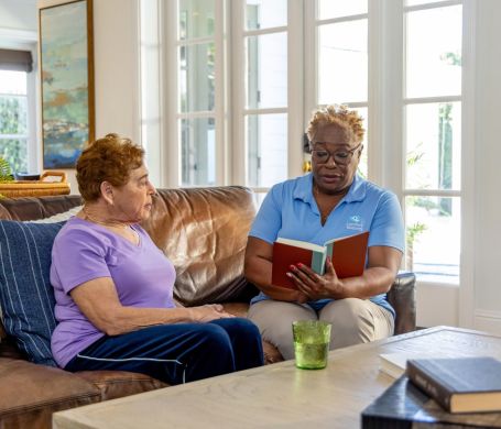 Comfort Keepers Caregiver reads a book to a client.