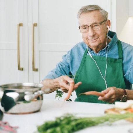 Senior Comfort Keepers clients enjoys cooking a meal in his kitchen with a caregiver.