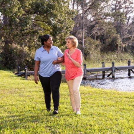 Comfort Keepers caregiver and client walk together and share a conversation outside. 