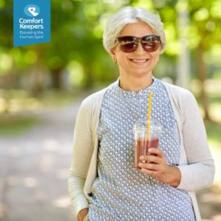 A senior enjoys her nutritional drink on a walk.