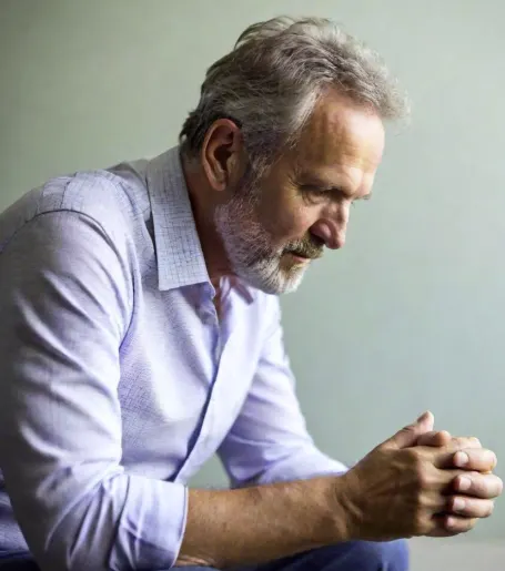Senior Seated with Clasped Hands Looking Down