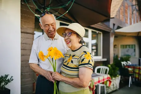 Senior Couple Holding Flowers Outside a Restaurant