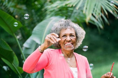 Senior blowing bubbles outside and smiling