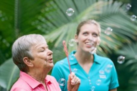 Senior and Caregiver Blowing Bubbles During Spring in Backyard