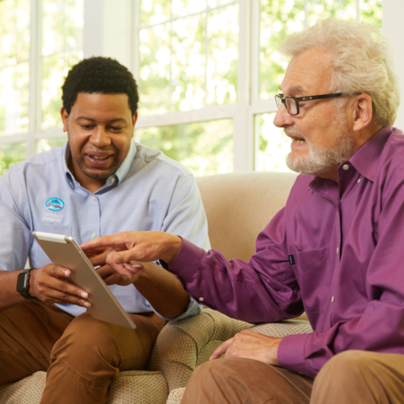 senior and caregiver reviewing something on the internet together