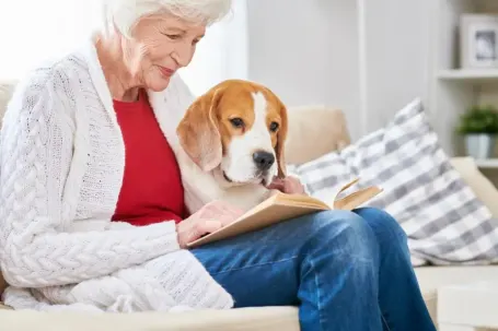 senior woman reading book with dog on her lap