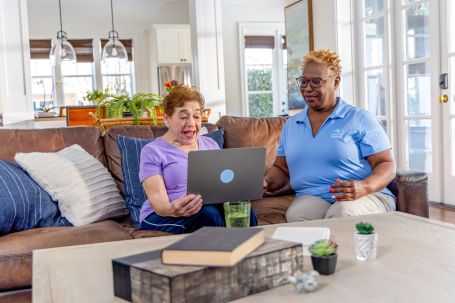 caregiver assisting senior woman on laptop