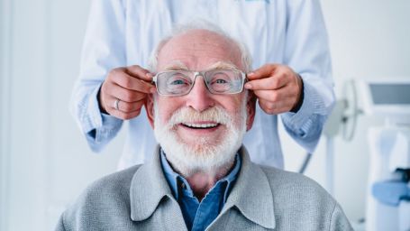 Senior man smiling while trying on glasses