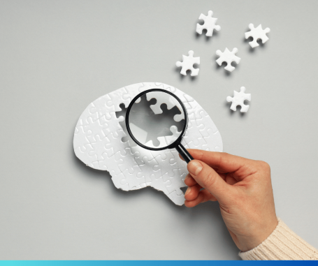 hand with magnifying glass over brain puzzle