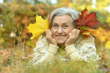 Senior laying in grass with fallen leaves