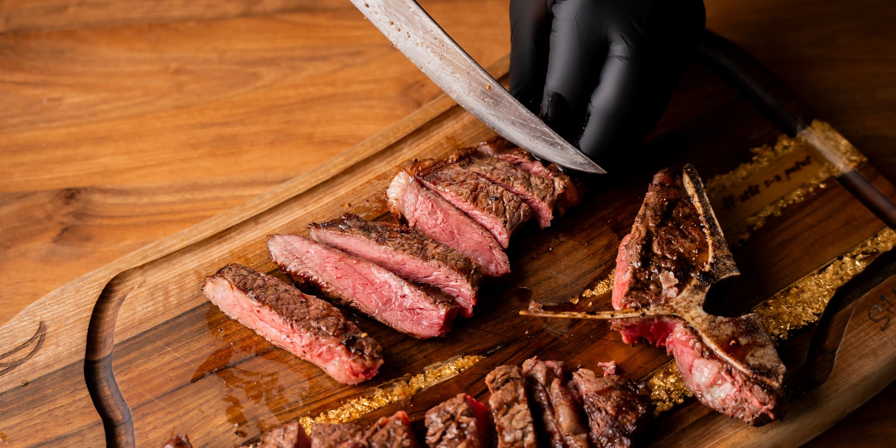 T-Bone tranșat pe platou de lemn cu foiță de aur · Transylvania Steakhouse