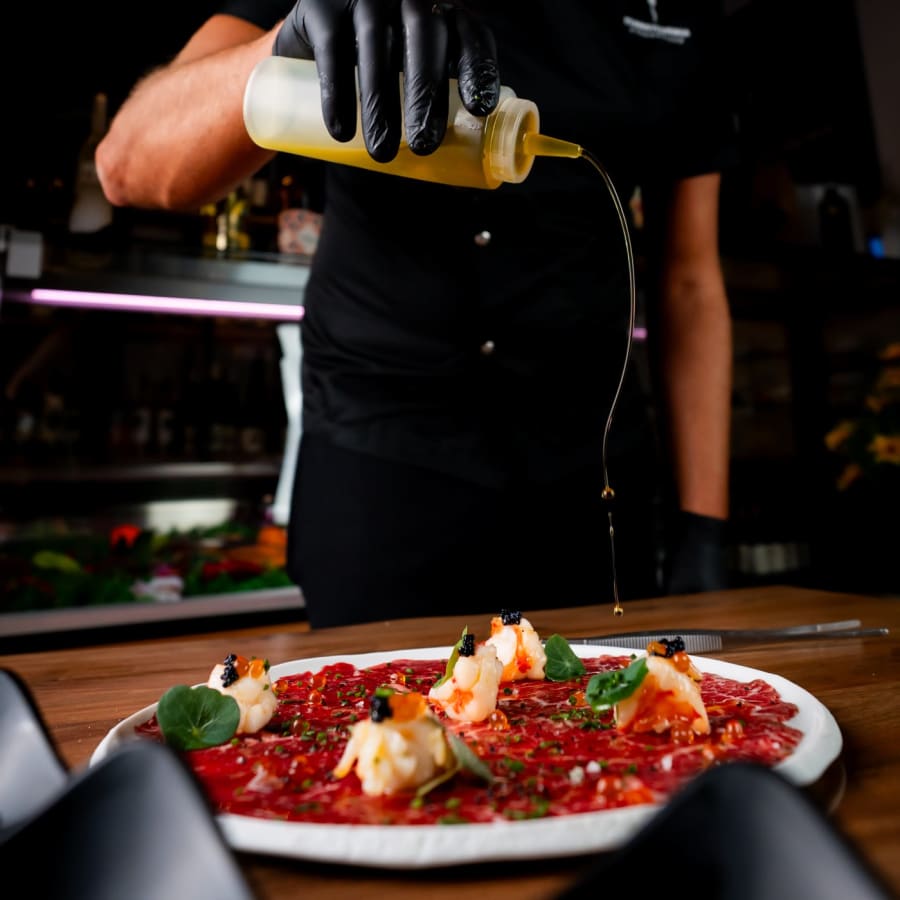 Carpaccio de Wagyu stropit cu ulei de măsline, la masă · Transylvania Steakhouse