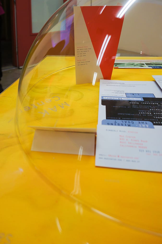 Gallery exhibition filled with plastic orbs and yellow vitrines