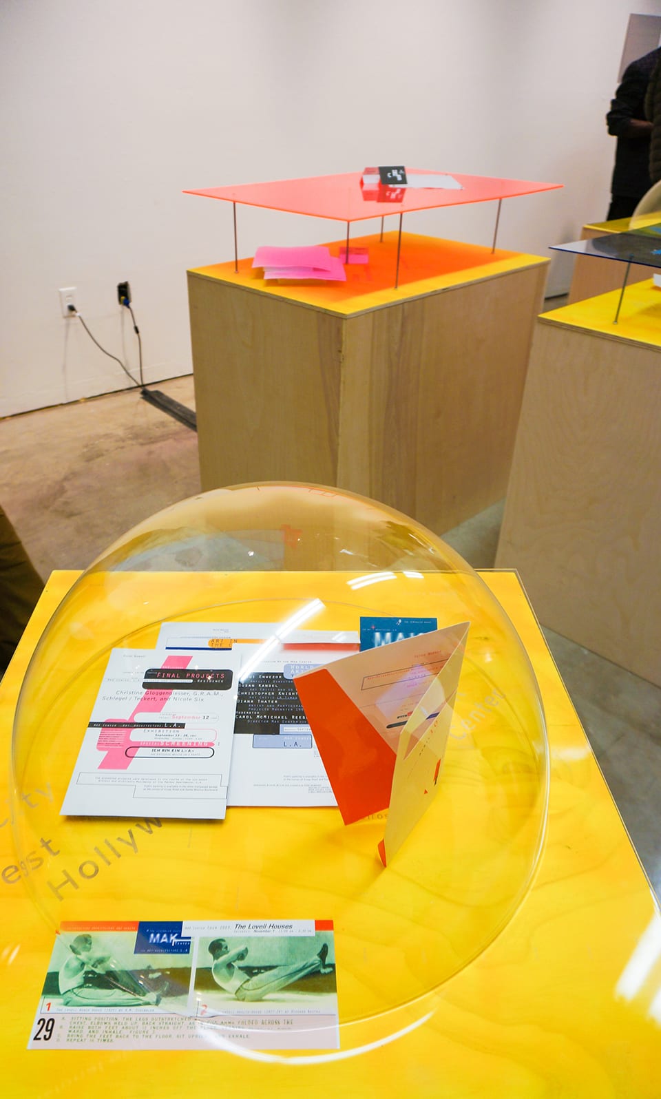 Gallery exhibition filled with plastic orbs and yellow vitrines
