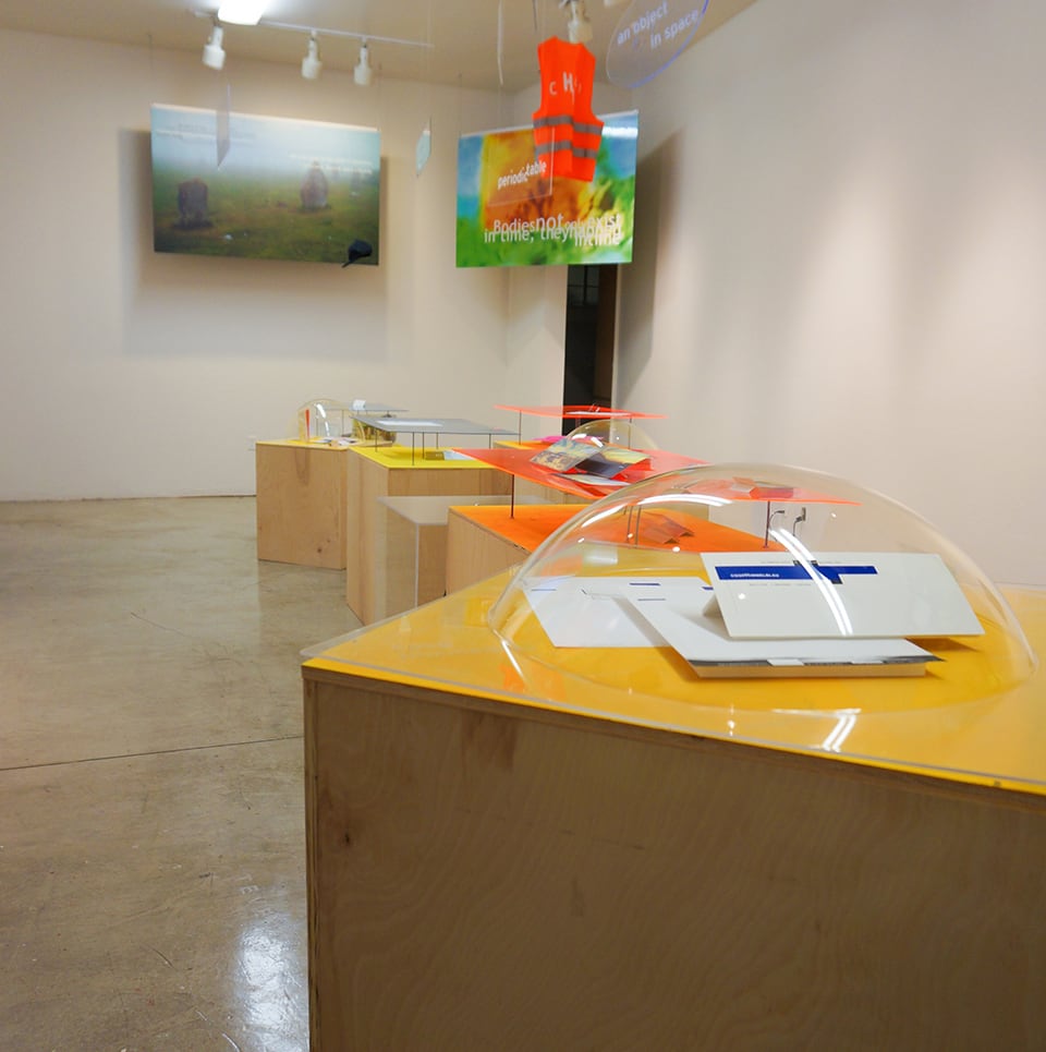Gallery exhibition filled with plastic orbs and yellow vitrines