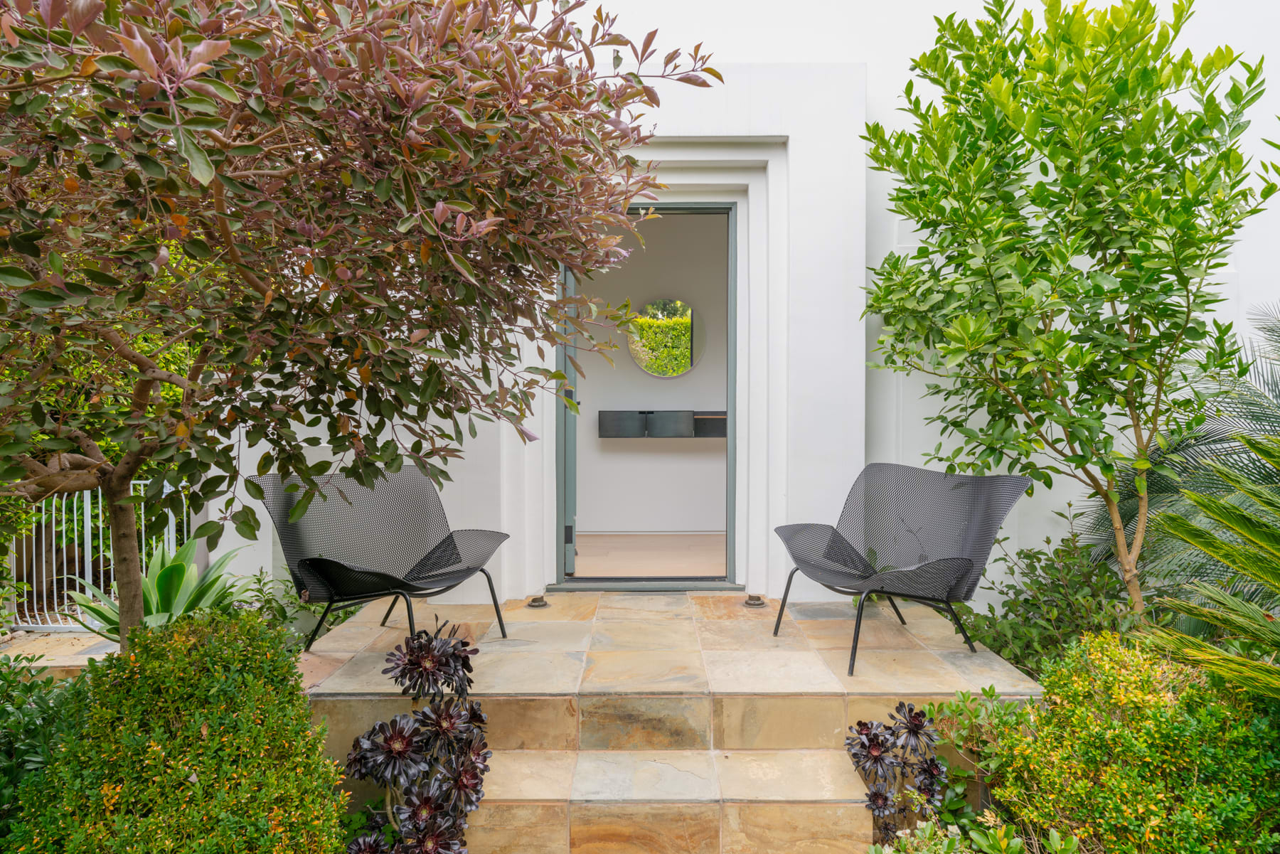 Front porch of house with open door and two benches