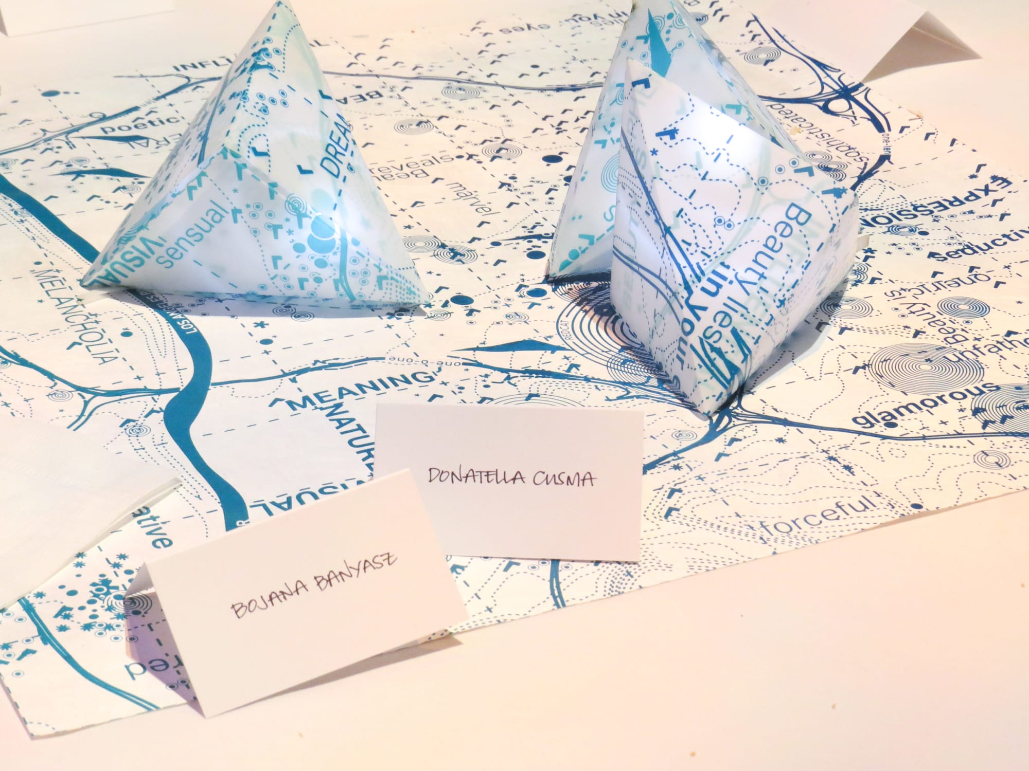 Folded paper maps on surface with name cards