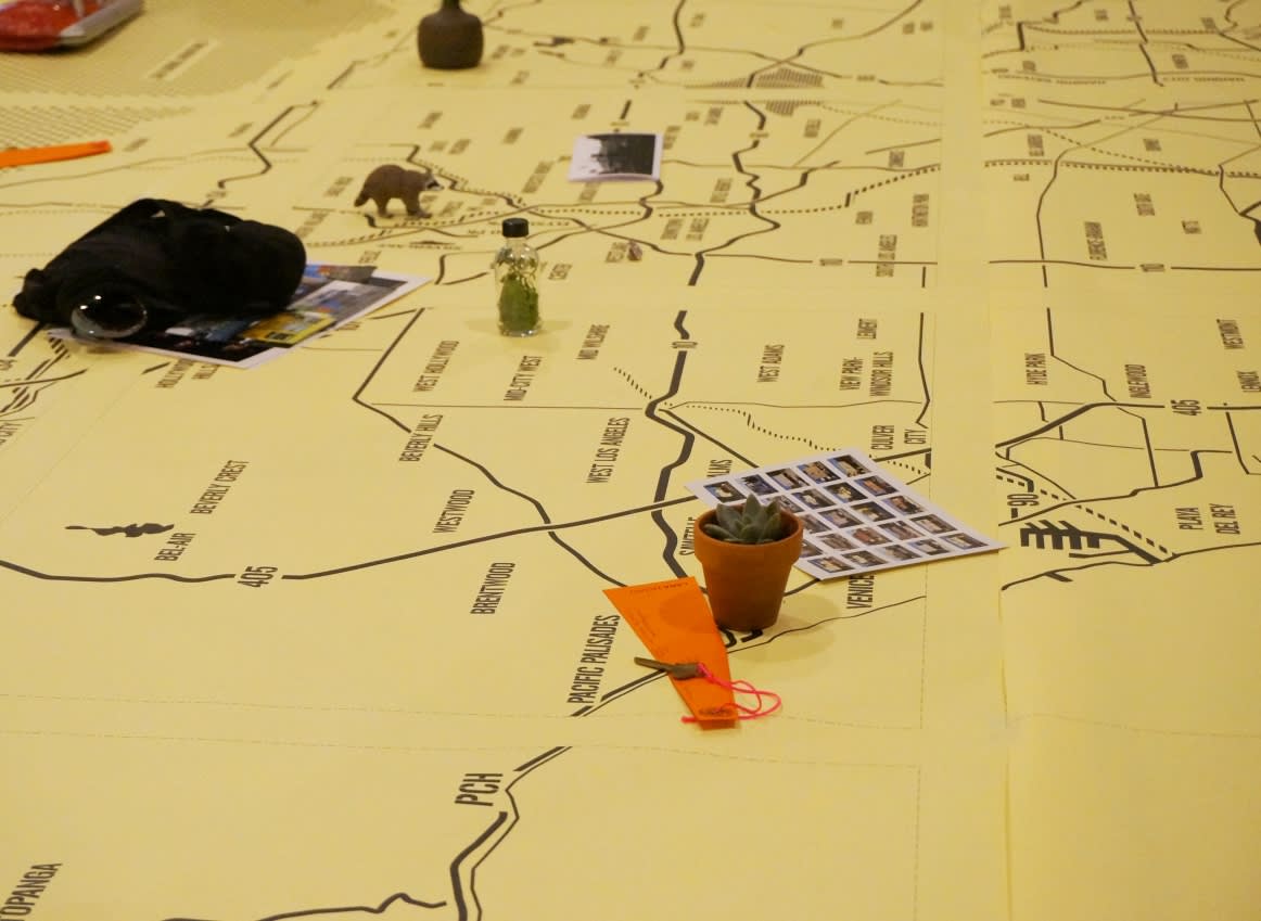 Guests seated around a giant map on a table (detail)